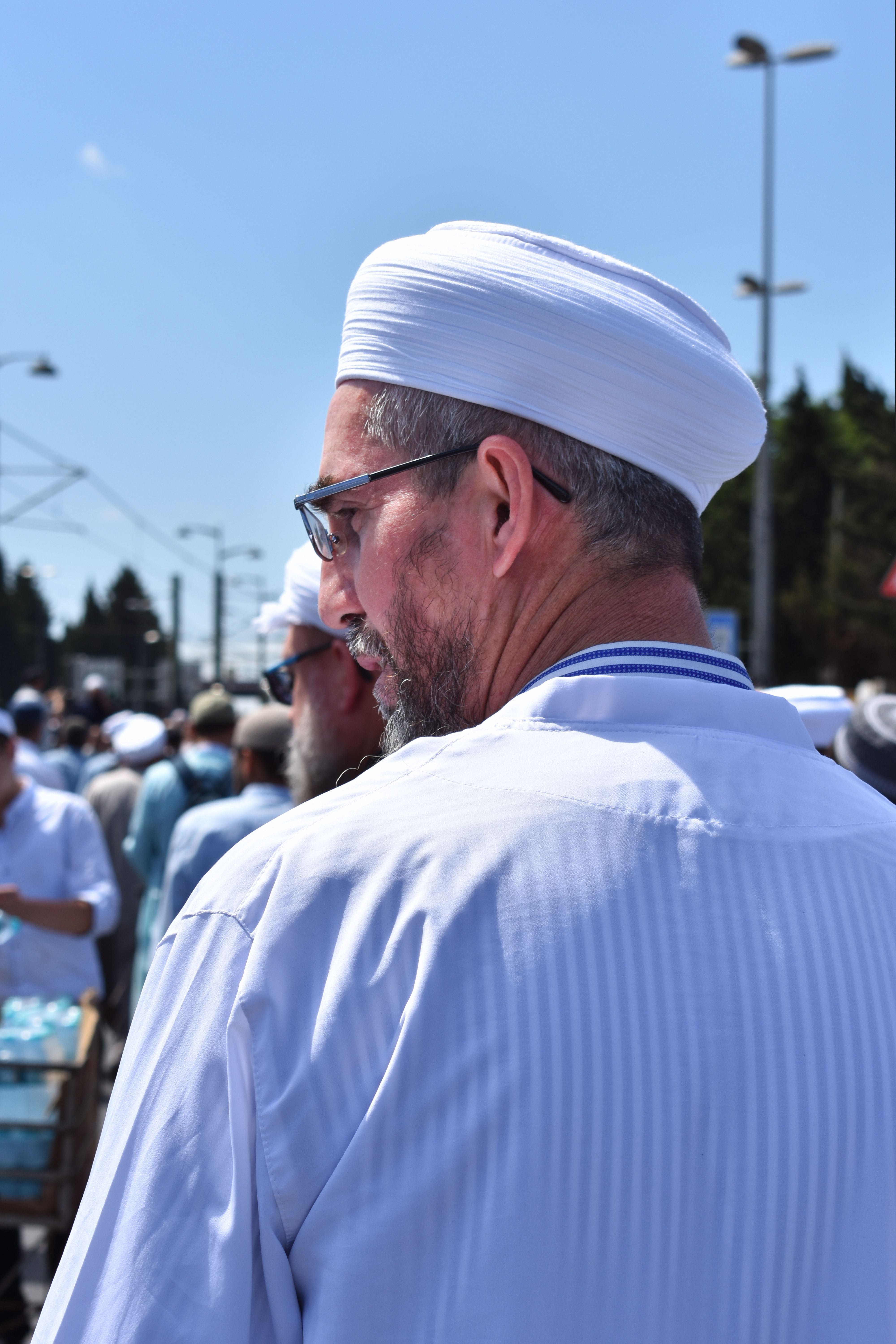 A man wearing a turban and white robe at an outdoor gathering in Istanbul, Türkiye.