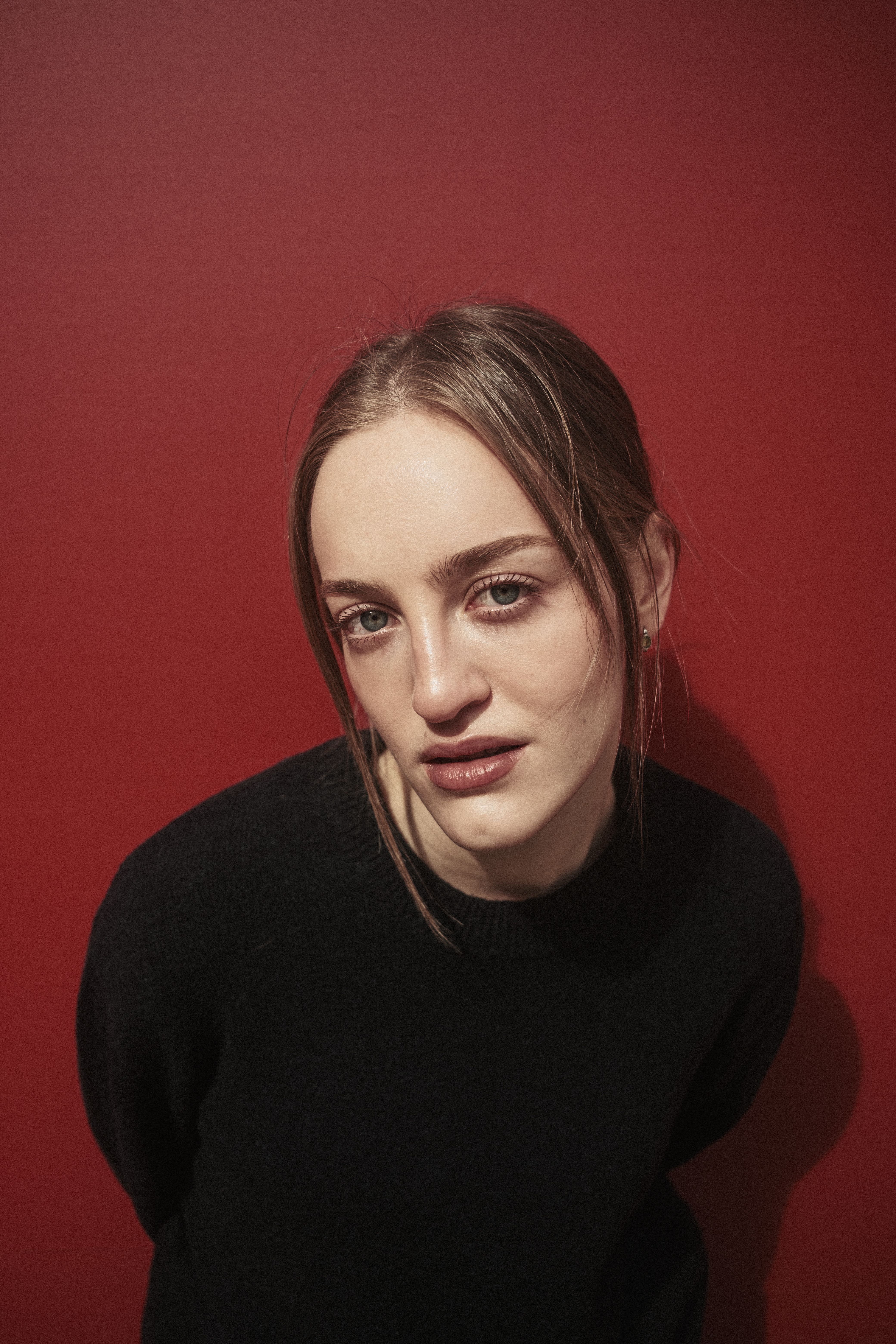 Stylish portrait of a woman in black against a vivid red wall.