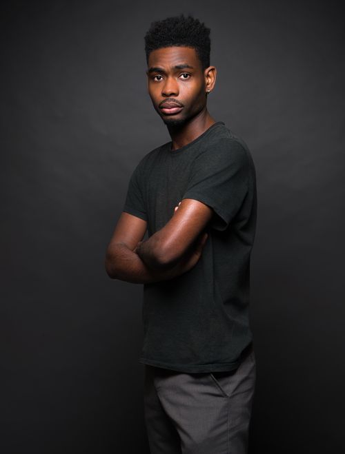 Free A fashionable young man poses confidently with crossed arms against a dark background. Stock Photo