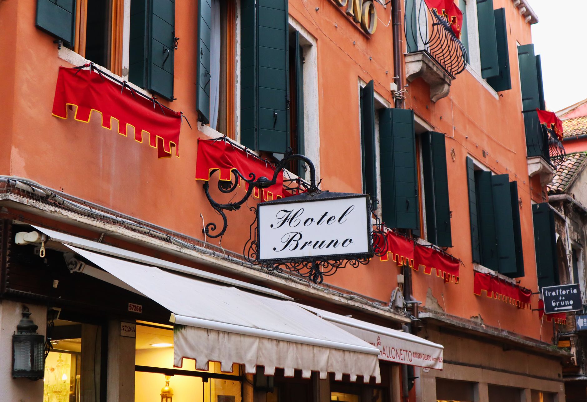 A picturesque Venetian hotel facade in Venice, Italy with red accents and classic architectural style.