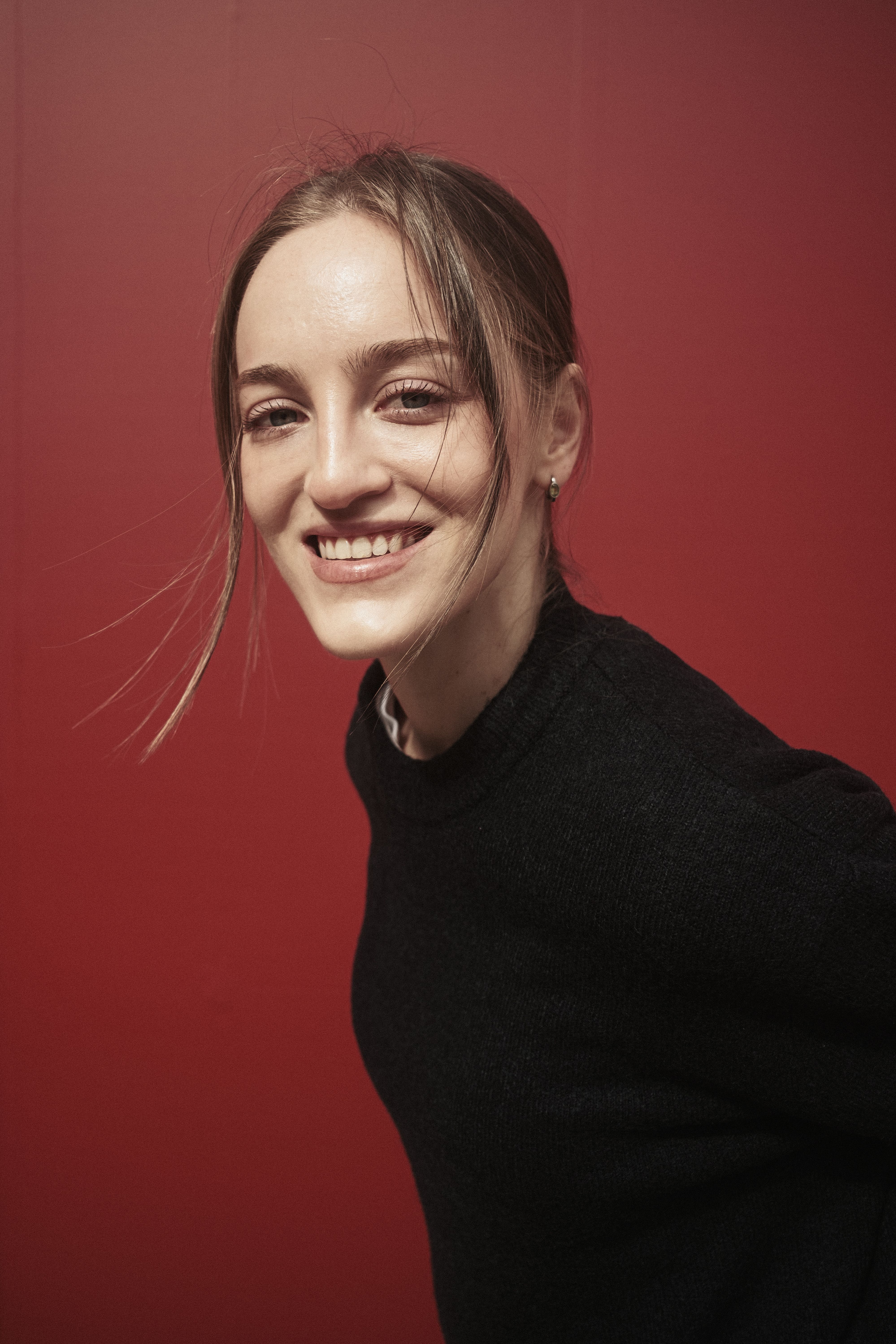Smiling woman posing against a vibrant red background in Istanbul.