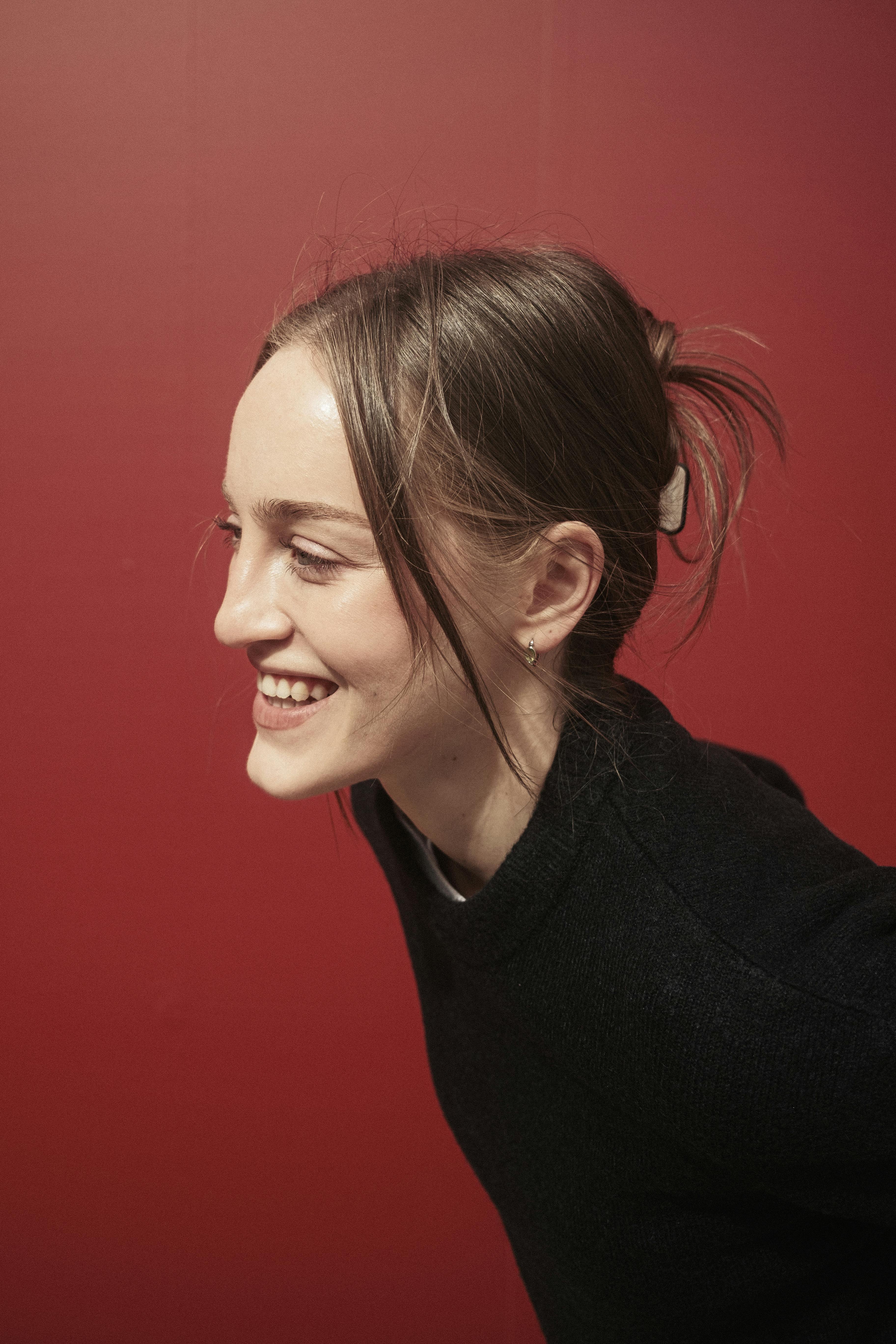 Portrait of a joyful woman against a bold red backdrop in Istanbul.