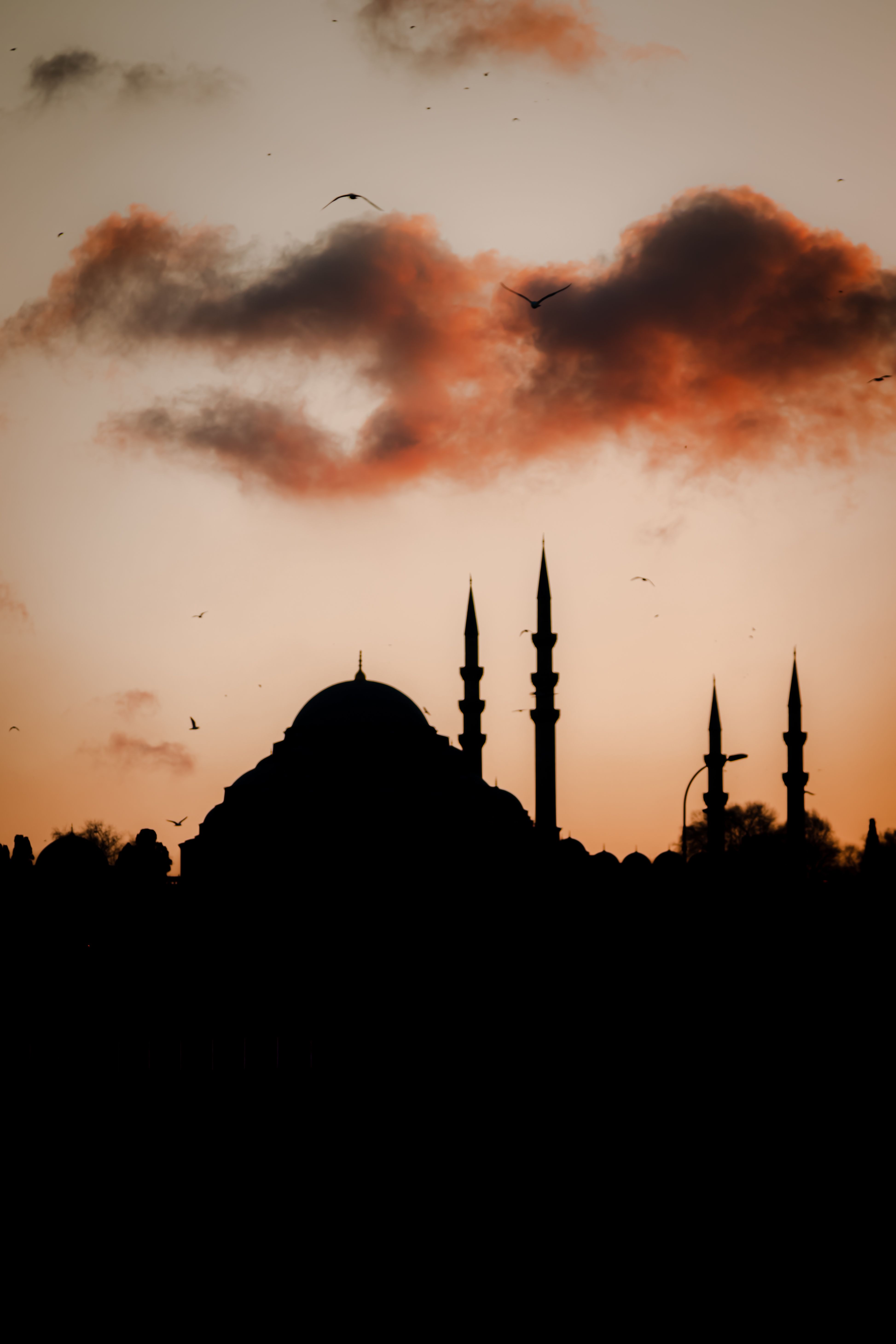 Silhouette of a mosque in Istanbul against a dramatic sunset sky.