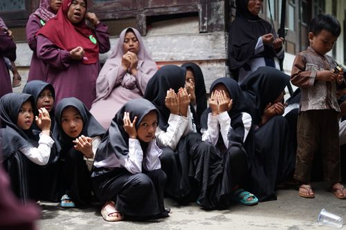 Free Children dressed in traditional clothing praying together outdoors, displaying cultural practices. Stock Photo