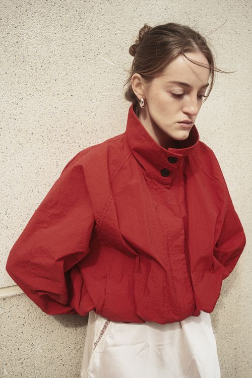 Free Woman in a stylish red jacket posing against a textured wall in Istanbul, Turkey. Stock Photo