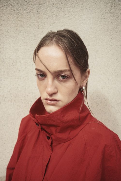 Free Portrait of a woman in a red coat against a textured wall, Istanbul. Stock Photo