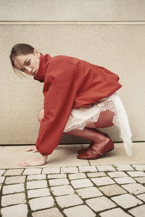 Free Stylish woman crouching in red outfit on cobblestone pavement, Istanbul. Stock Photo