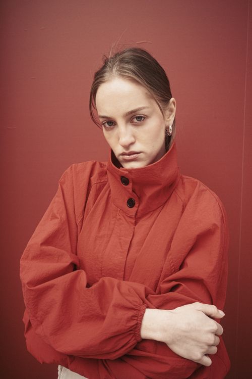 Free Stylish woman in red jacket posing indoors against a red background in Istanbul. Stock Photo