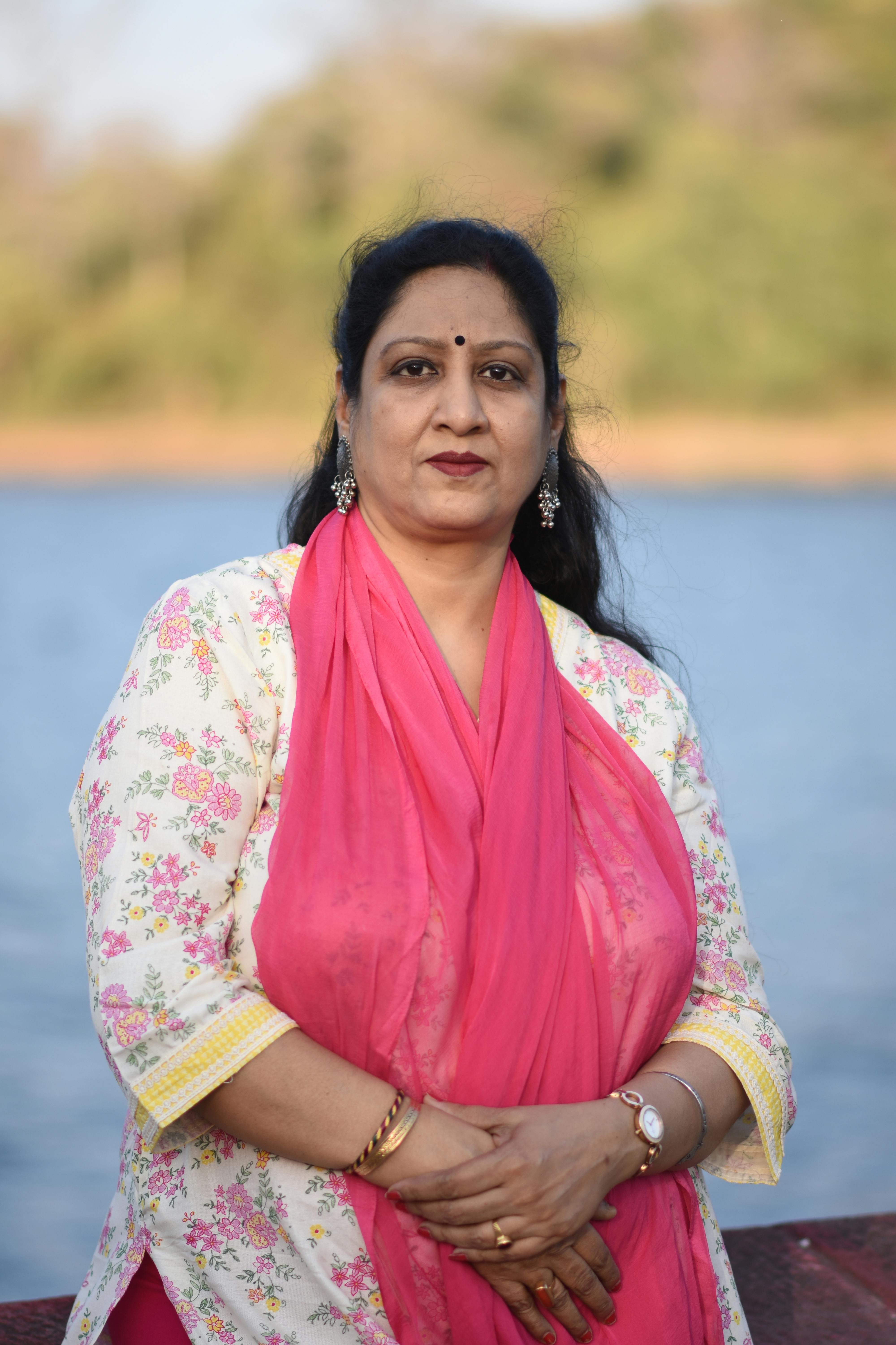 A serene portrait of a woman wearing traditional Indian clothing, standing by a lake.