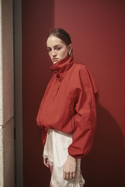 Stylish woman in a red jacket posing against a red wall in Istanbul, Turkey.