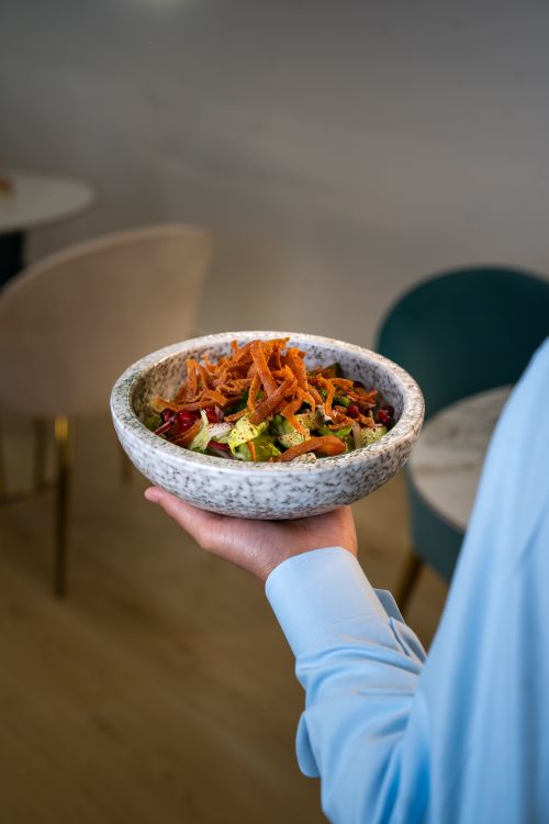 Free Colorful vegetable salad held by a person indoors, showcasing healthy eating in a modern dining environment. Stock Photo