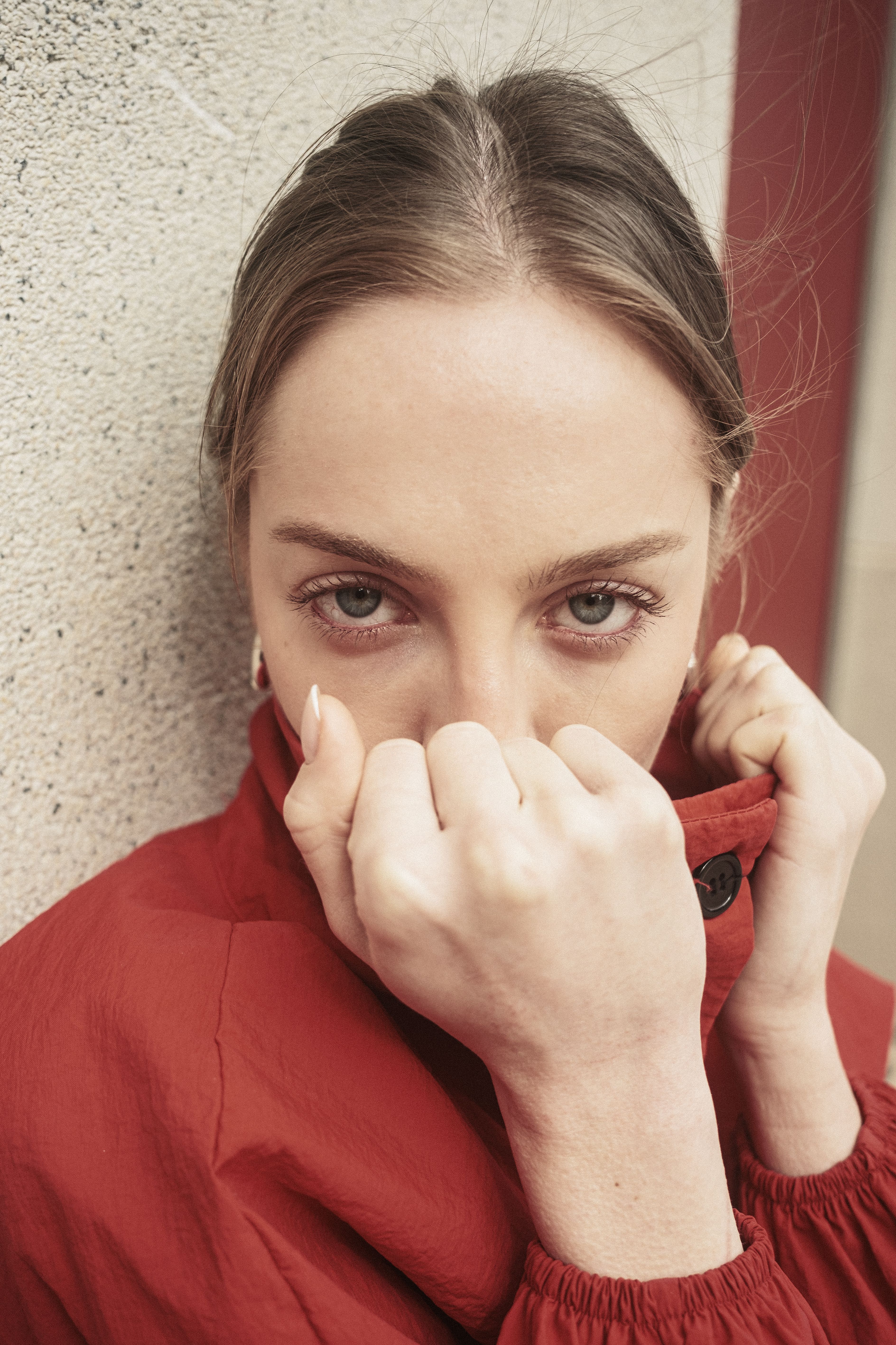 Close-up portrait of a woman with green eyes in a red jacket, exuding confidence.