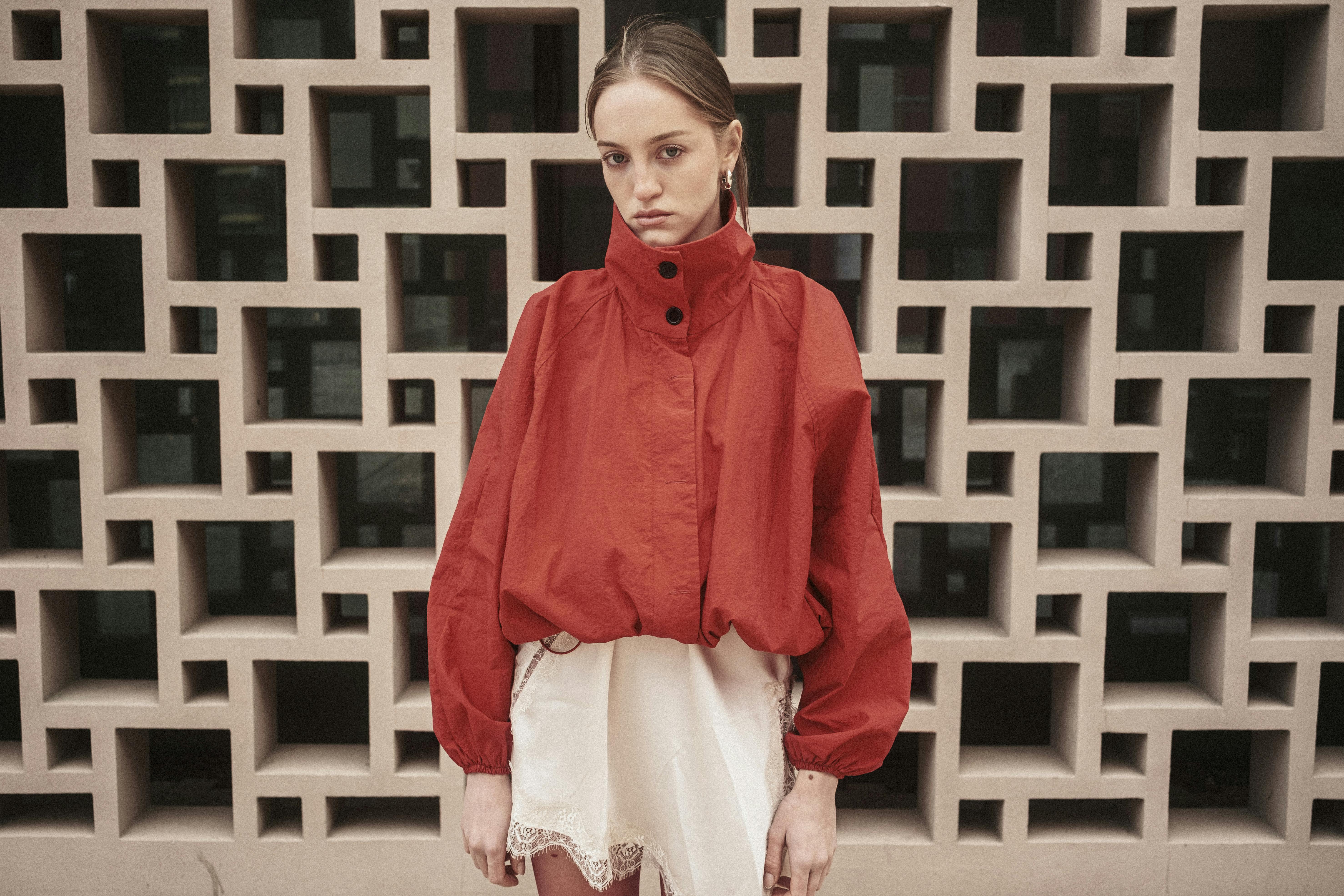 Gratis Una donna alla moda con una giacca rossa posa contro un muro geometrico a Istanbul. Foto a disposizione