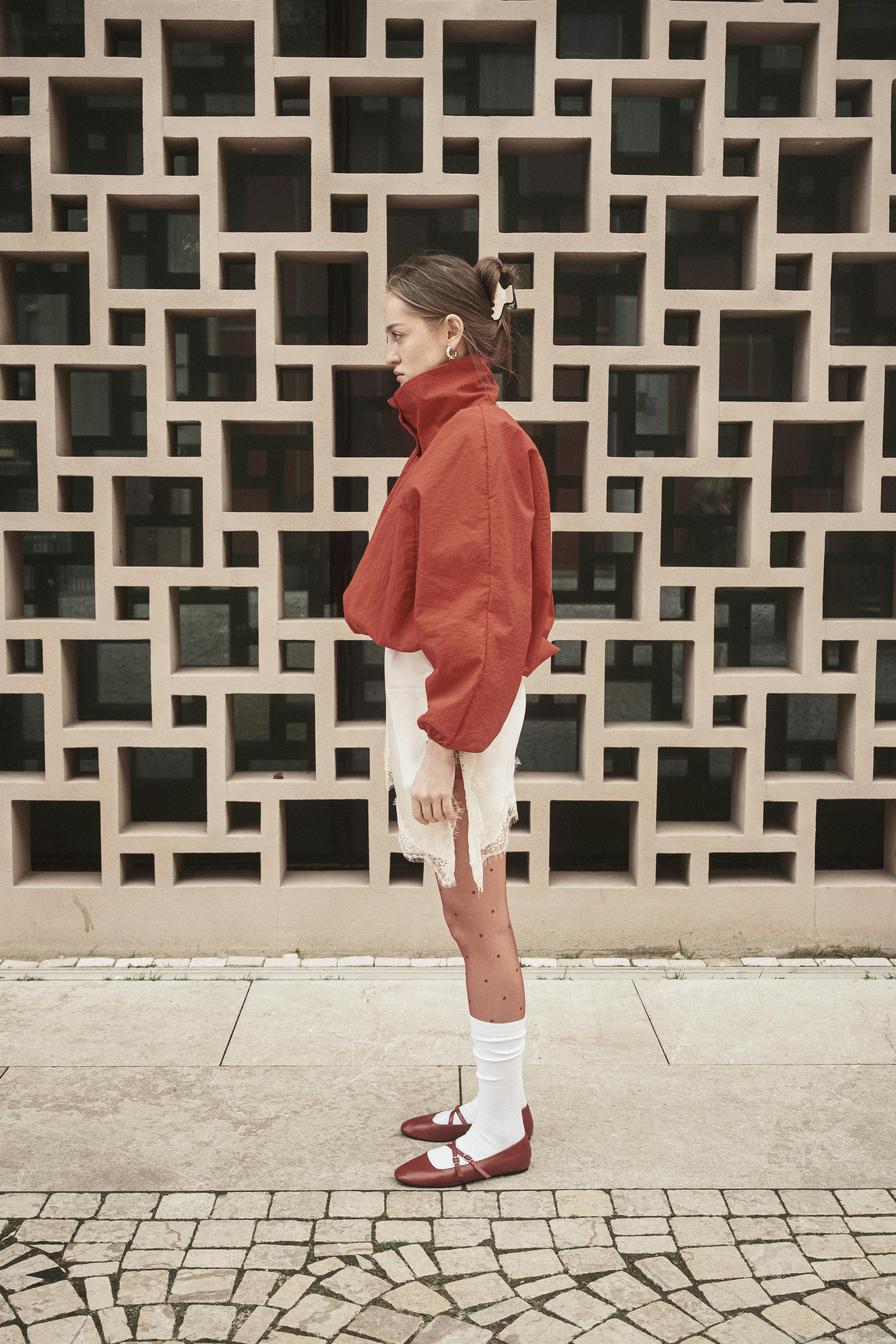 Gratis Una donna elegante con una giacca rossa posa contro un muro geometrico a Istanbul, in Turchia. Foto a disposizione