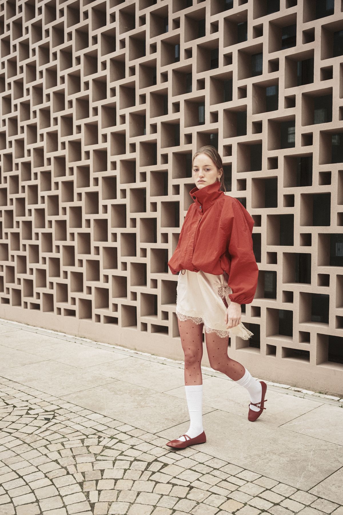 A fashionable woman walking by a geometric wall — the loafer, styled