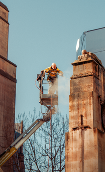 Worker jet washing stonework