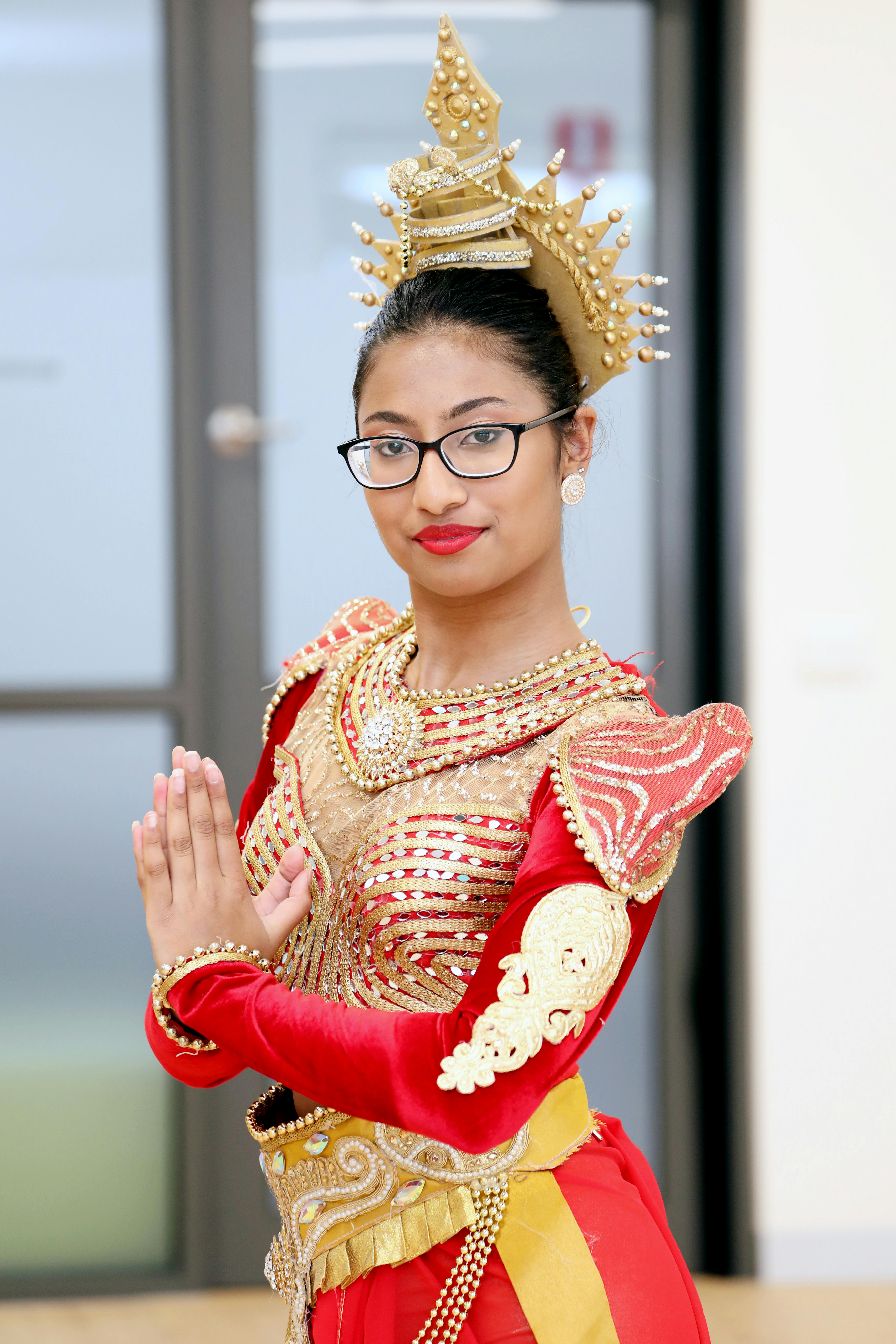 Woman in traditional Cambodian dance attire posing indoors with ornate headdress.