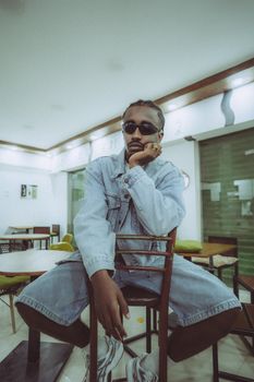 Moody portrait of a young man in denim, captured indoors showcasing streetwear style.