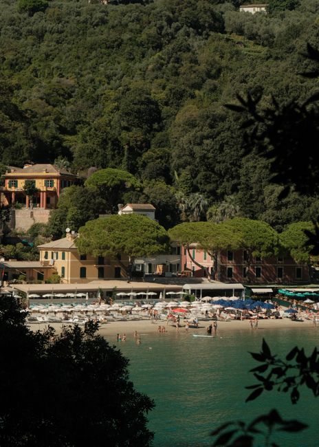 Relaxed beach scene in Portofino, Italy surrounded by lush greenery and classic architecture.