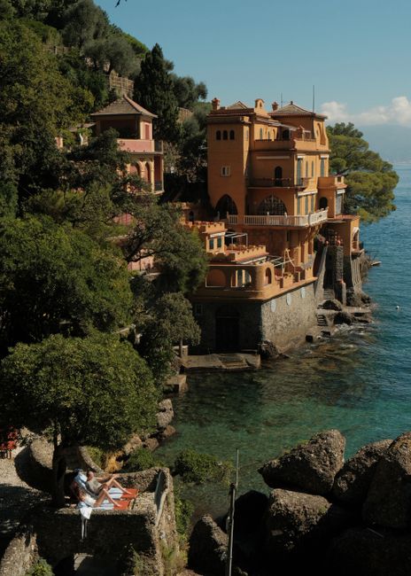 Beautiful villa on the rocky coast of Portofino, Italy, surrounded by lush greenery and turquoise sea.