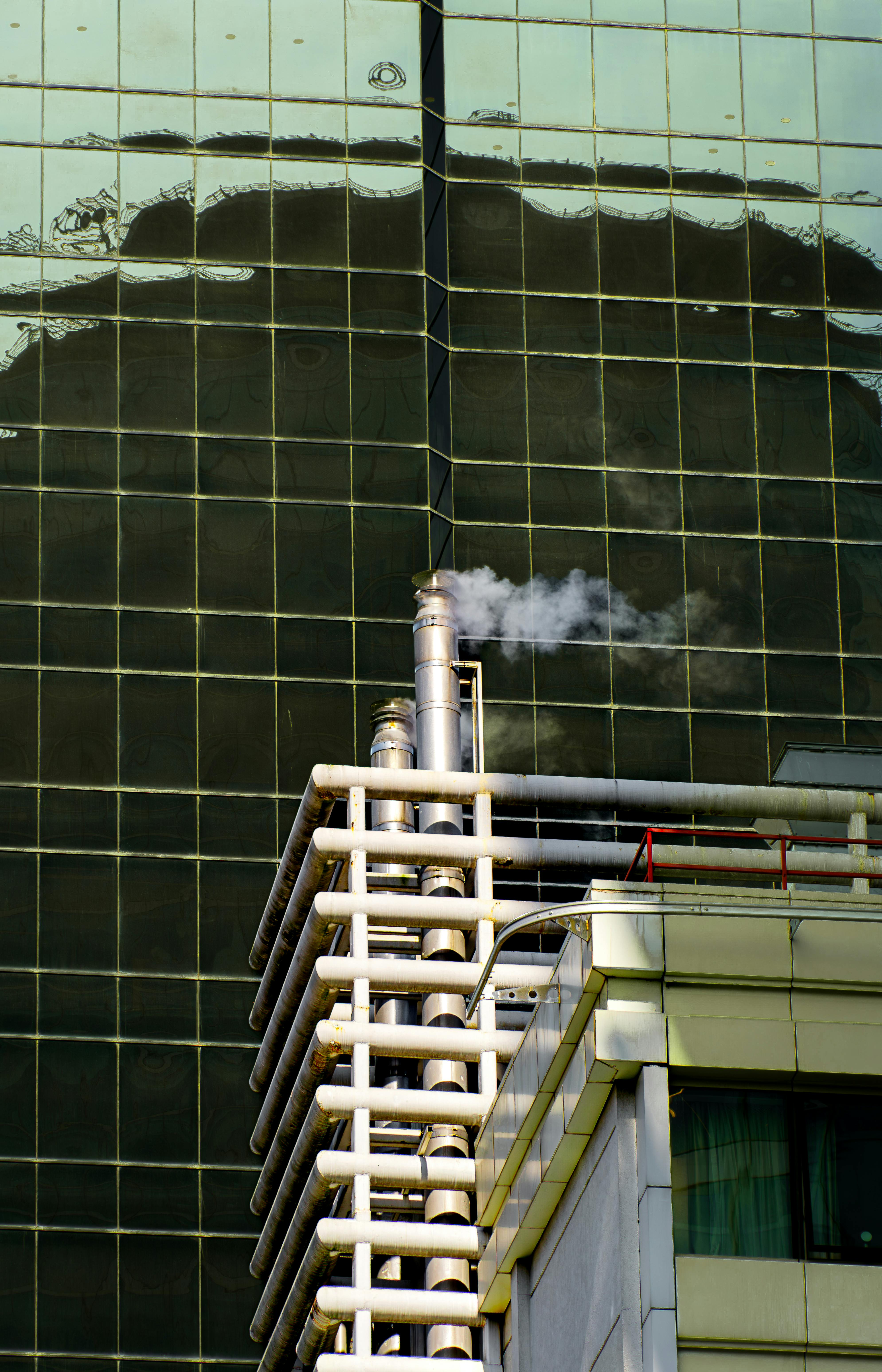 Industrial pipes emitting steam on a modern building showing real-world steam measurement environment where vortex flow monitors are installed