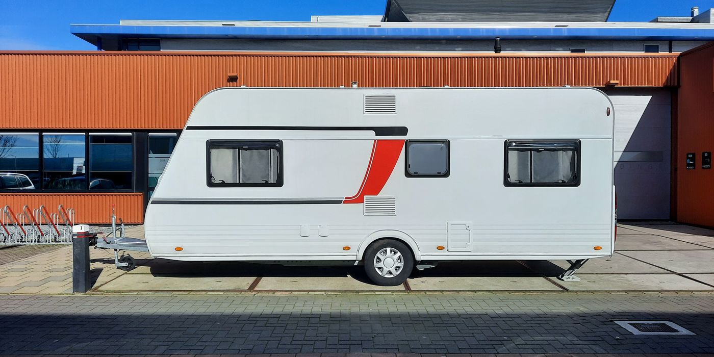 A white travel trailer parked side-on, showing its smooth sidewall