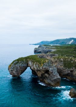 Stunning aerial shot of Asturian coastline showcasing natural rock formations and ocean waves.
