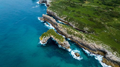 Free A breathtaking aerial shot of the rocky coastline of Spain's northern region, showcasing natural arches and vibrant blue waters. Stock Photo