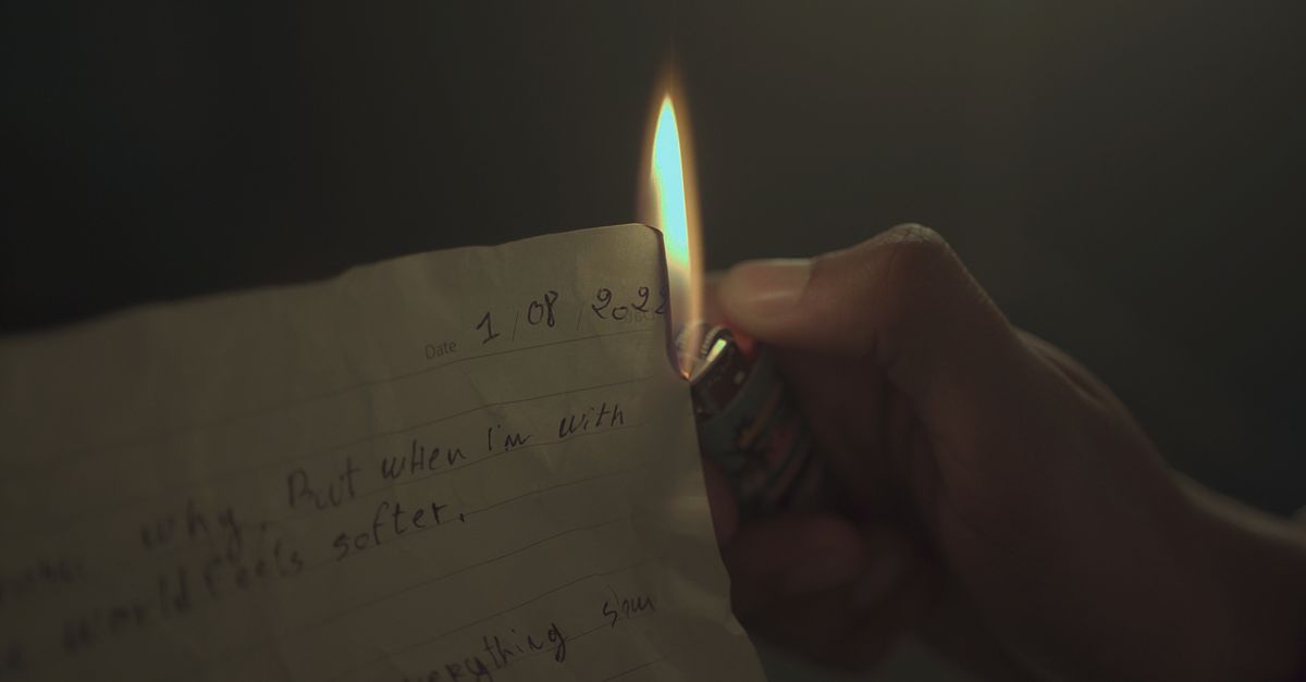 person burning a piece of paper in a bowl, symbolic release