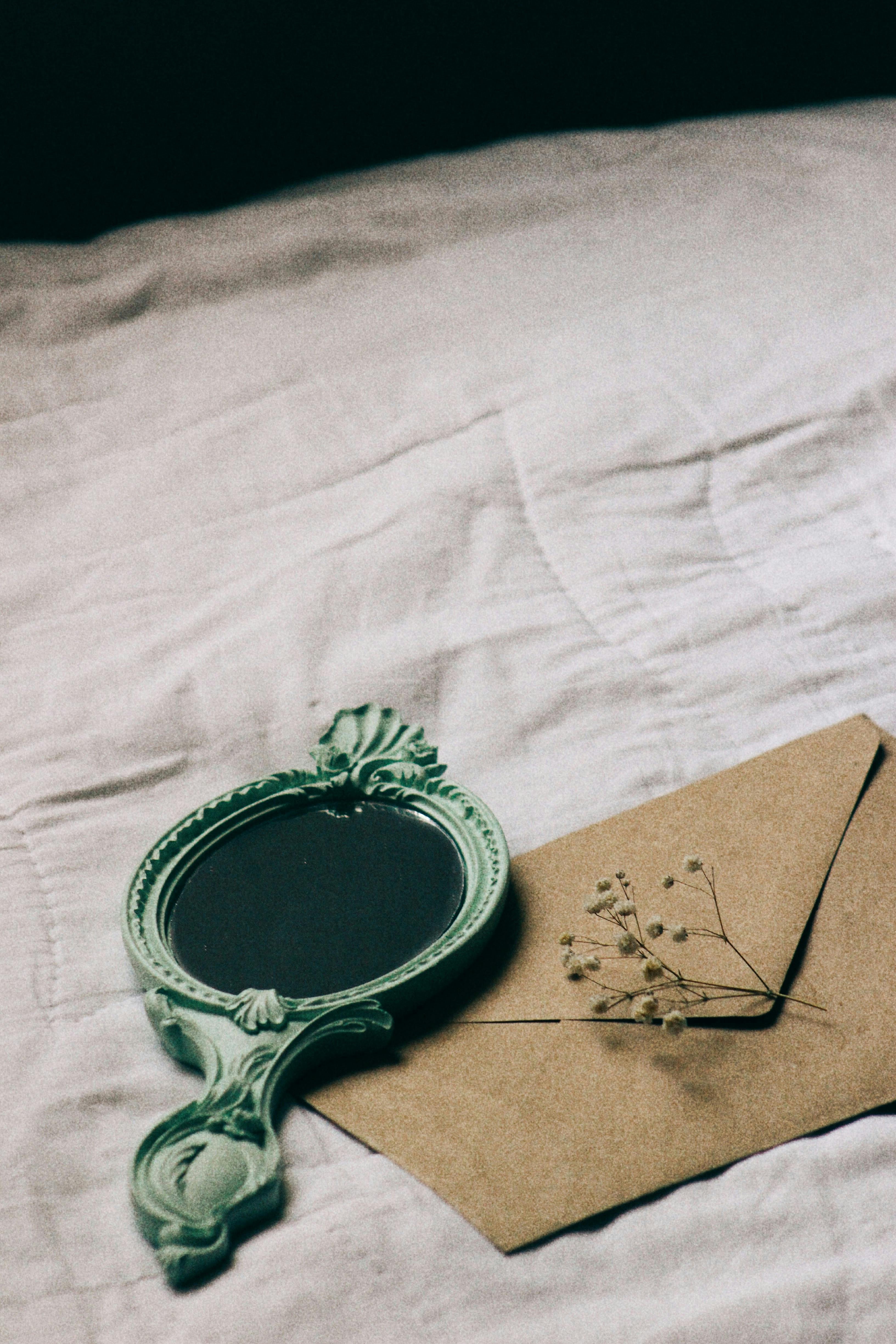 Artistic arrangement of a retro mirror and envelope on white fabric, evoking nostalgia.