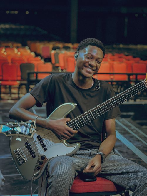 Free Smiling young musician holding a guitar, seated in an empty concert hall in Accra, Ghana. Stock Photo