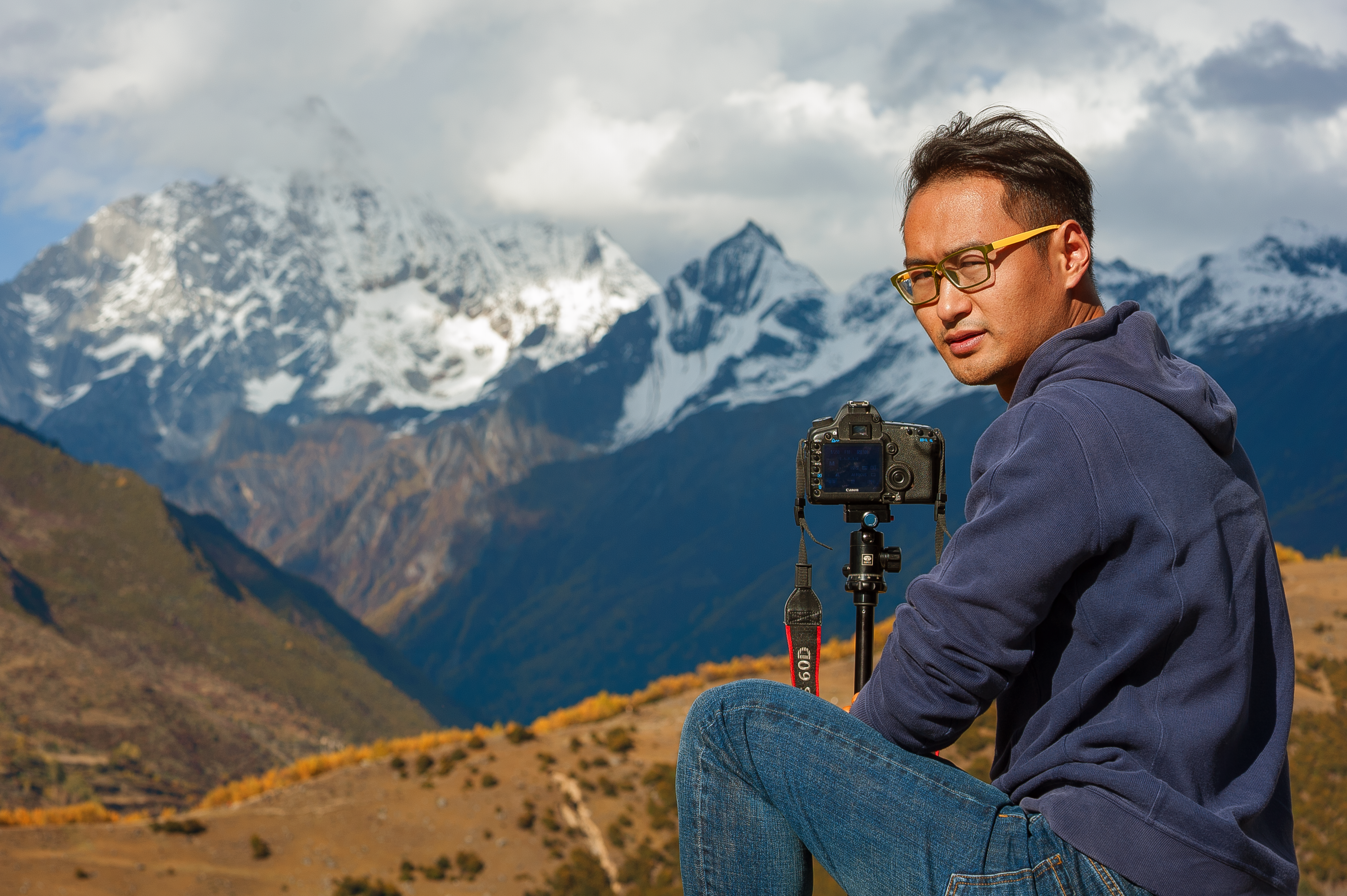 Photographer with camera captures stunning mountain landscape in Garzê Tibetan Autonomous Prefecture, Sichuan.