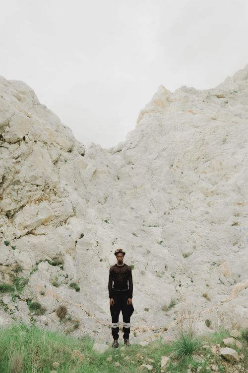 Free Man standing alone in front of a rugged mountainous backdrop in Greece, embracing solitude. Stock Photo