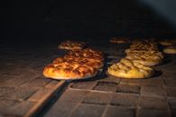 Golden brown bread being baked in a traditional stone oven, showcasing artisanal craftsmanship.