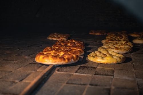 Free Golden brown bread being baked in a traditional stone oven, showcasing artisanal craftsmanship. Stock Photo