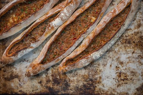 Free Close-up of several Turkish pide with delicious meat filling on a rustic tray. Stock Photo