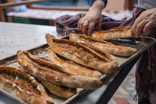 Free Hands preparing freshly baked pide bread on a baking tray in a traditional kitchen setting. Stock Photo