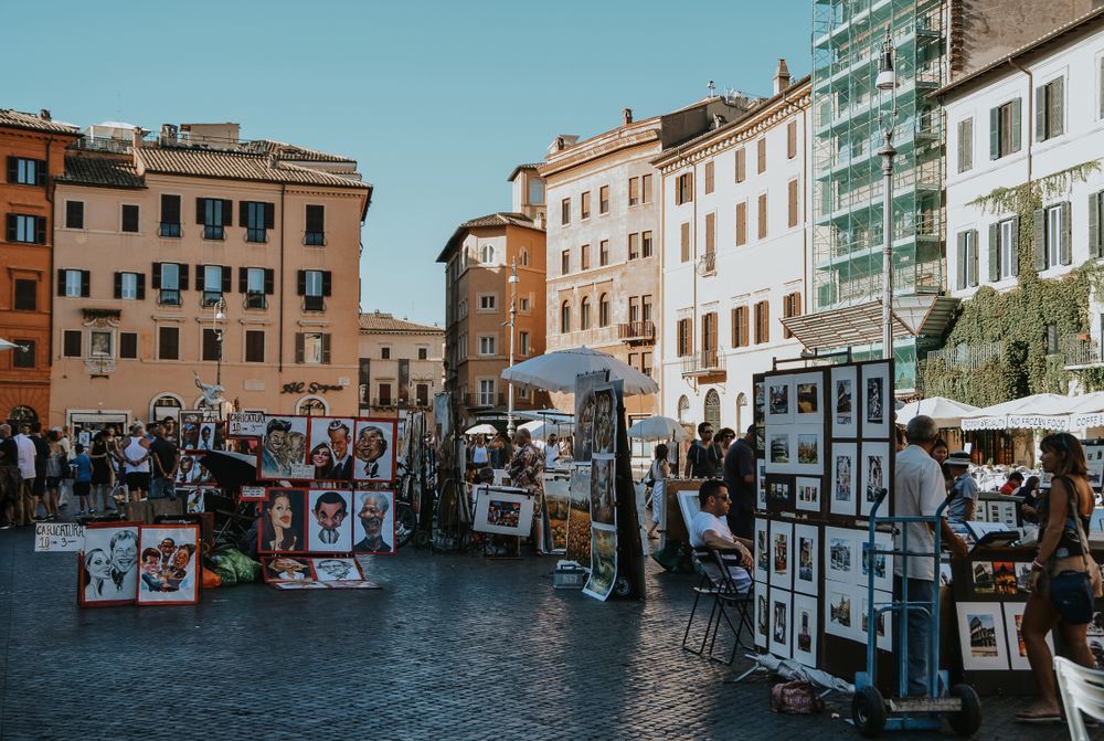 Piață animată într-o piațetă istorică din Roma, cu tarabe și vizitatori