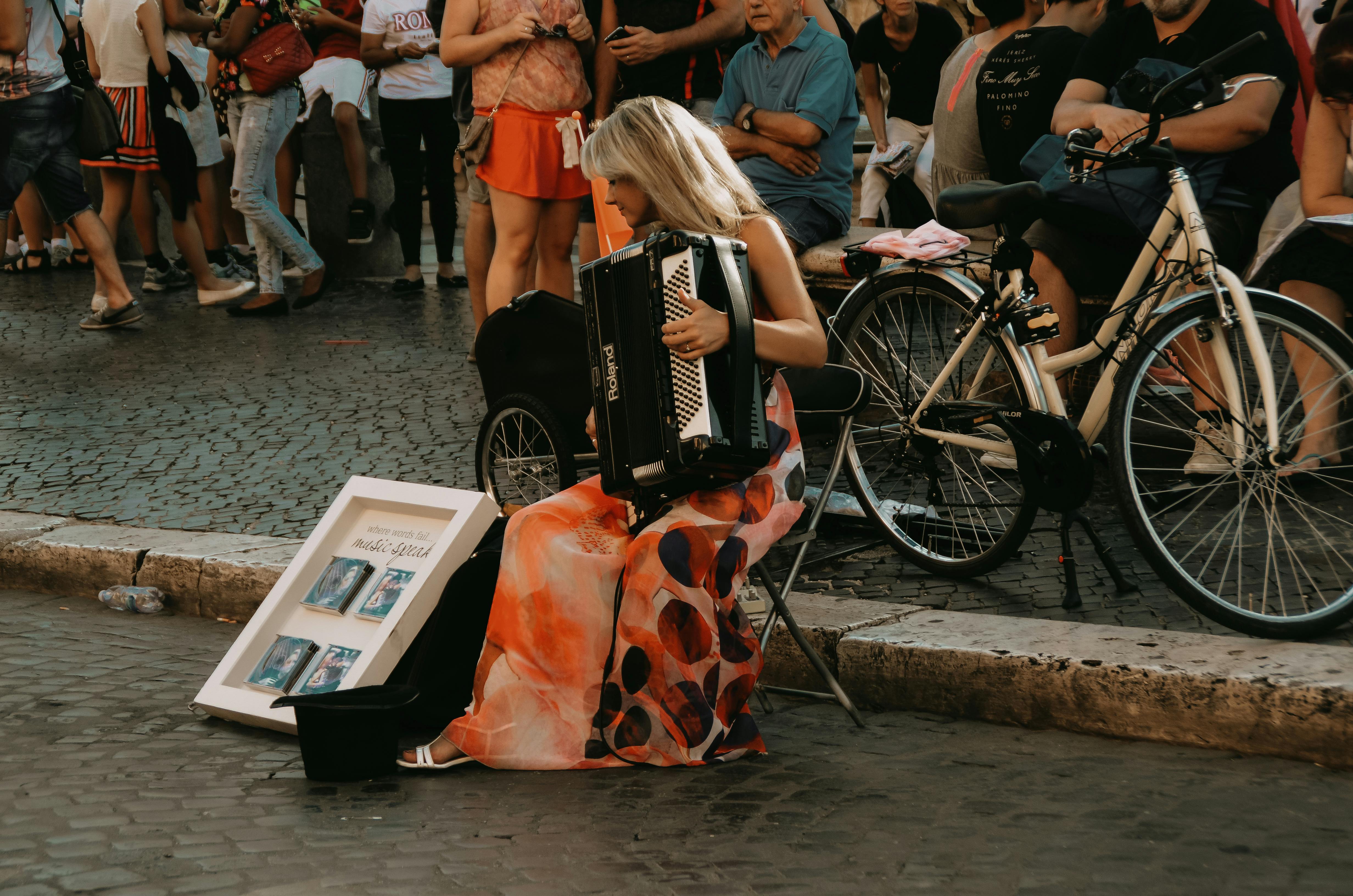 無料 イタリアのローマで、活気に満ちた群衆の中でアコーディオンを演奏するストリートミュージシャン。 写真素材