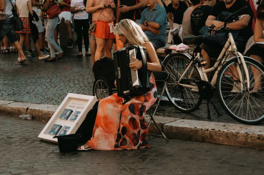 A street musician performing with an accordion in a vibrant crowd in Rome, Italy.