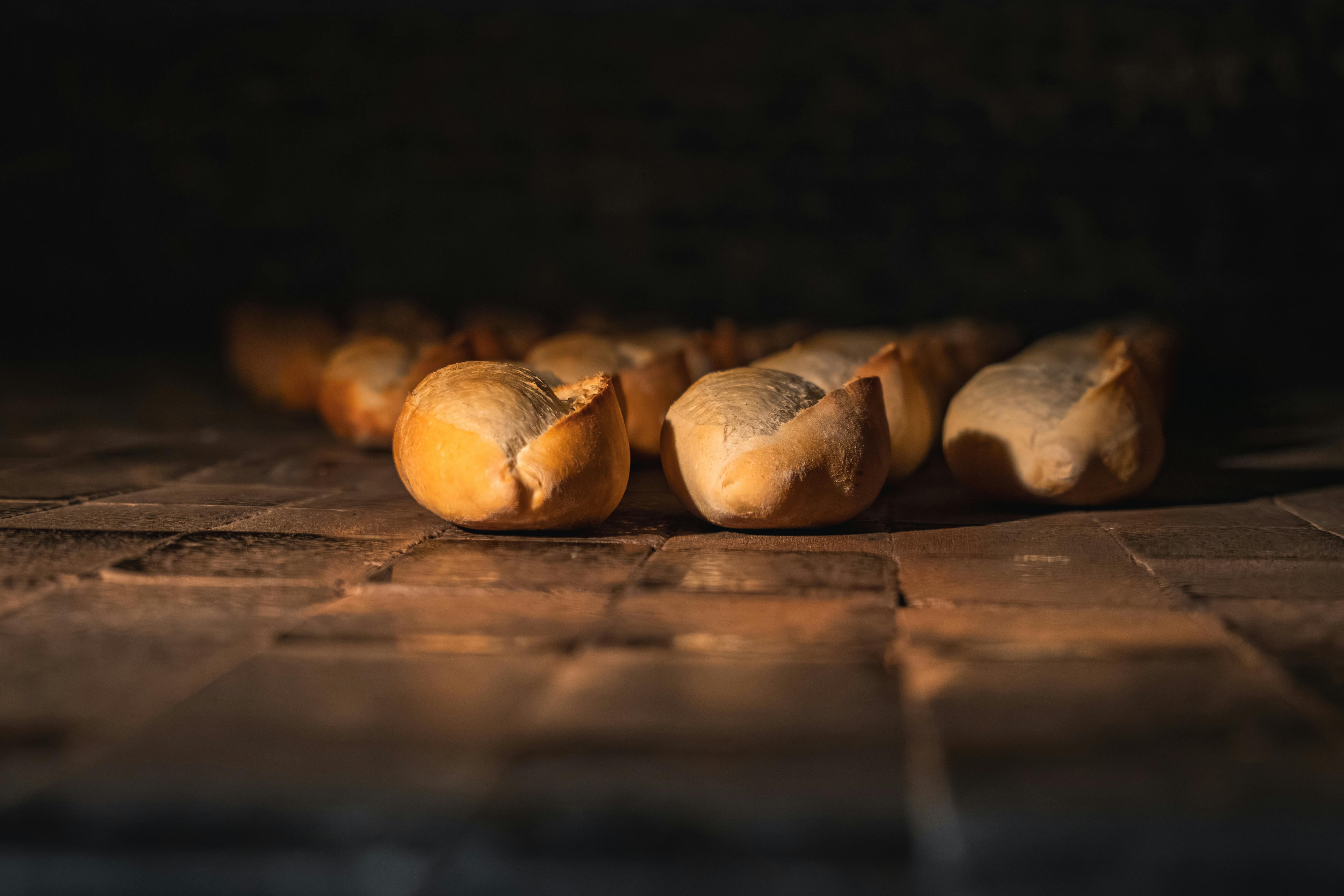 Gratis Panini dorati cotti in un forno tradizionale con luci calde e soffuse, che creano un'atmosfera accogliente in cucina. Foto a disposizione