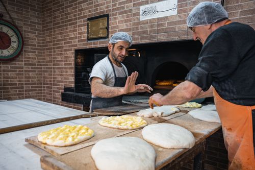 Free Two bakers making traditional flatbread in a stone oven, showcasing a classic bakery setting. Stock Photo