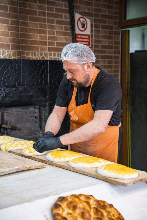 Free A baker wearing an apron and hairnet prepares traditional bread in an artisan bakery. Stock Photo