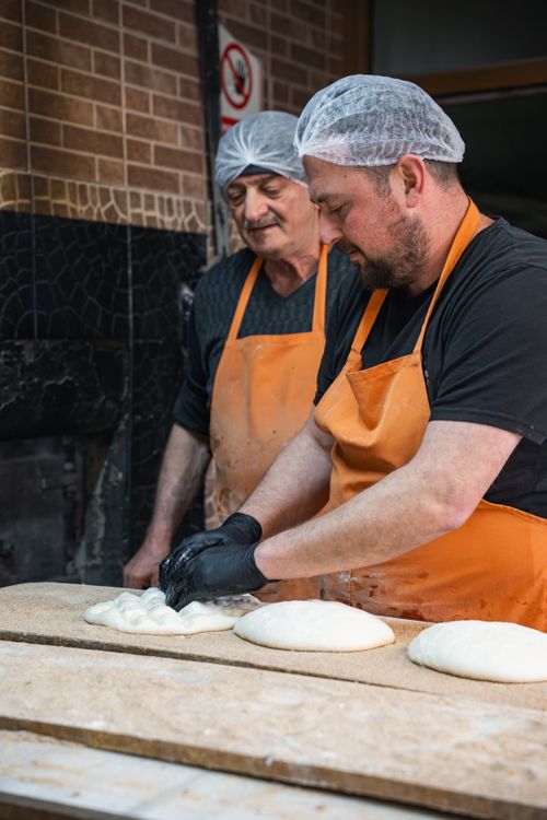 Free Two bakers shape dough in a traditional bakery setting, highlighting artisanal bread-making techniques. Stock Photo