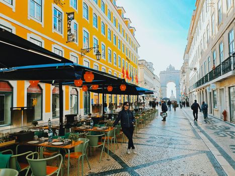 A bustling street scene in Lisbon, Portugal featuring iconic architecture and a cozy café.