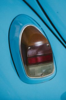 Detail view of a classic blue Volkswagen Beetle tail light showcasing vintage automotive design.