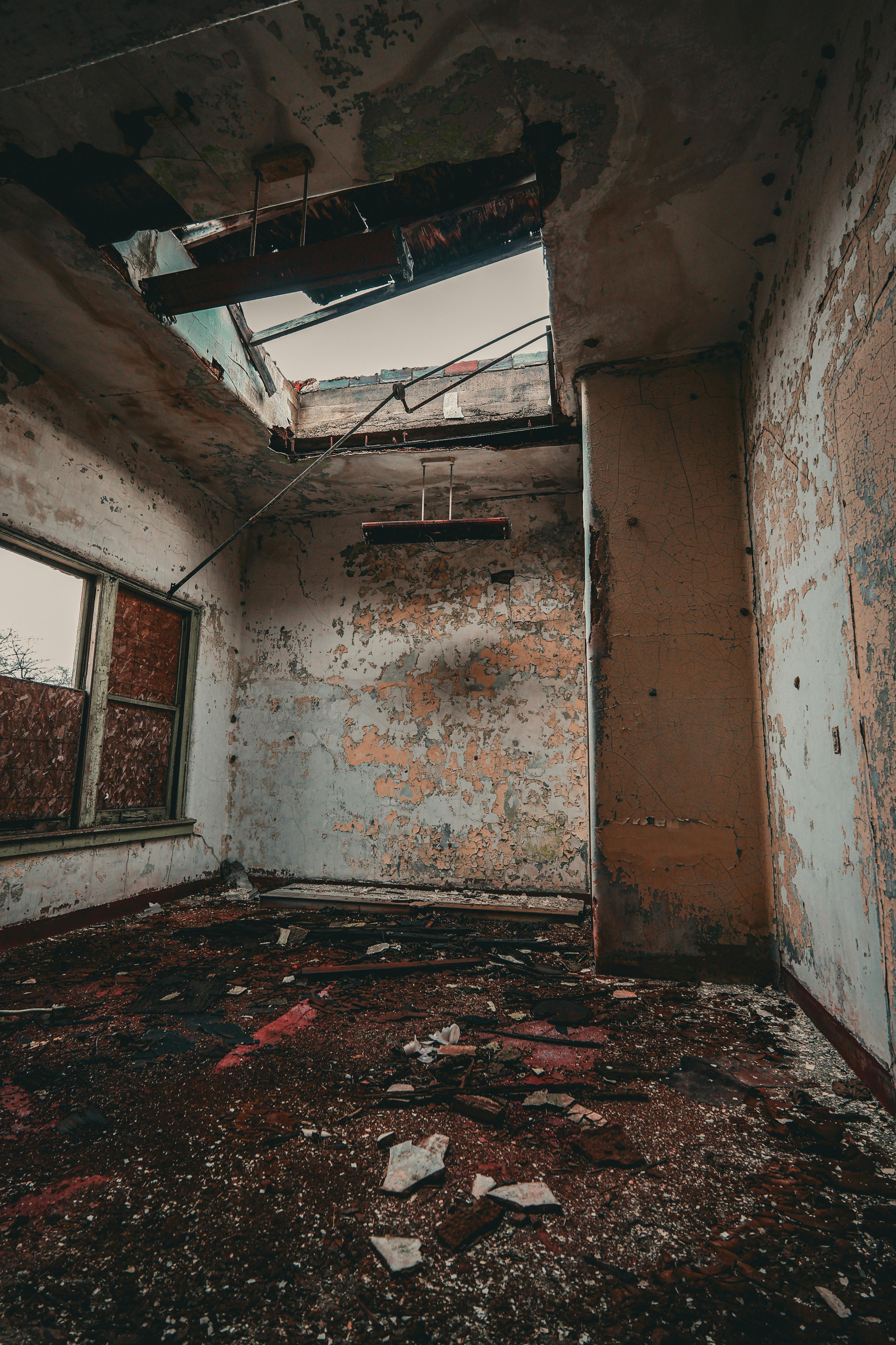 Gratis Esplora questa stanza inquietante e decadente, con il tetto danneggiato e le pareti scrostate, che cattura il degrado e l'abbandono urbano. Foto a disposizione