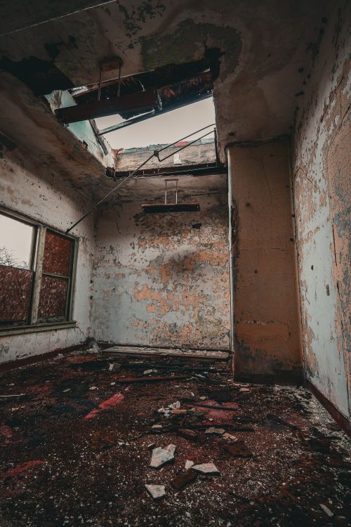 Free Explore this eerie, decayed room with a damaged roof and peeling walls, capturing urban decay and abandonment. Stock Photo