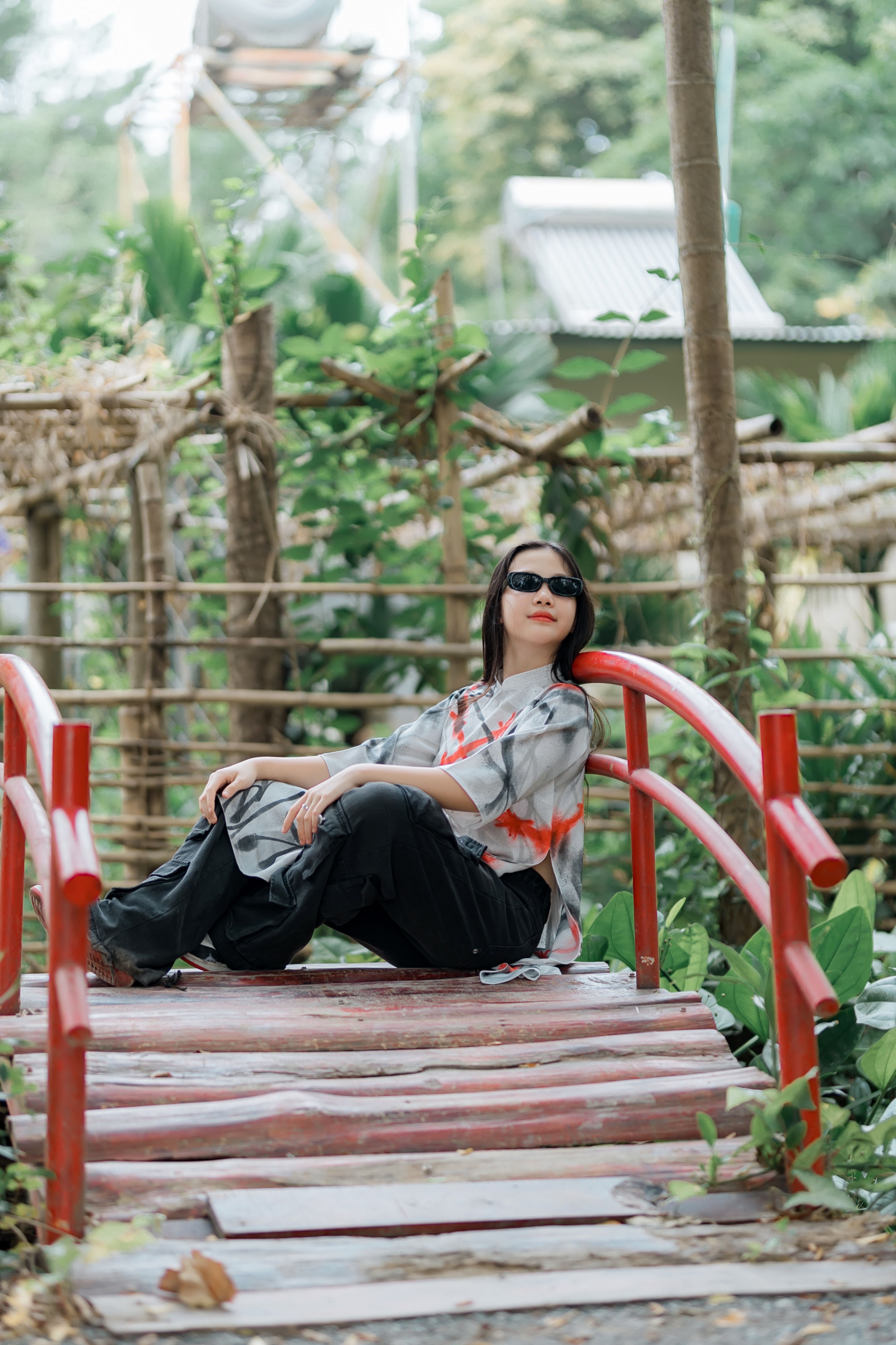 Woman Relaxing on a Vibrant Red Bridge in Nature · Free Stock Photo