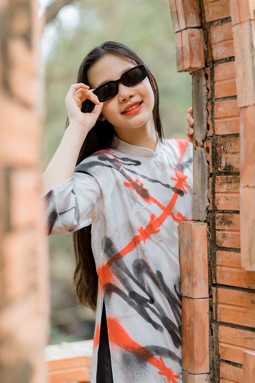 Free Stylish young woman in sunglasses poses by a rustic brick wall, exuding modern fashion. Stock Photo